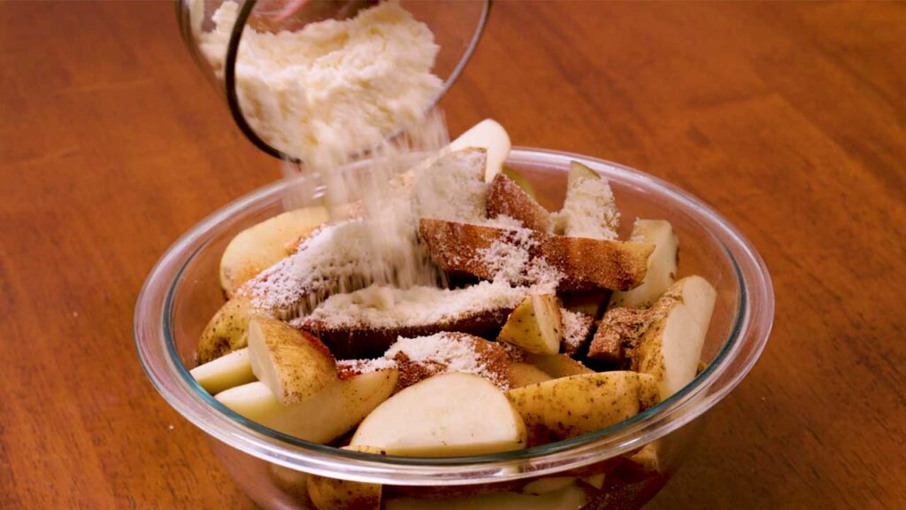 How to make potato wedges – step 2: tossing cut potatoes with olive oil and seasonings