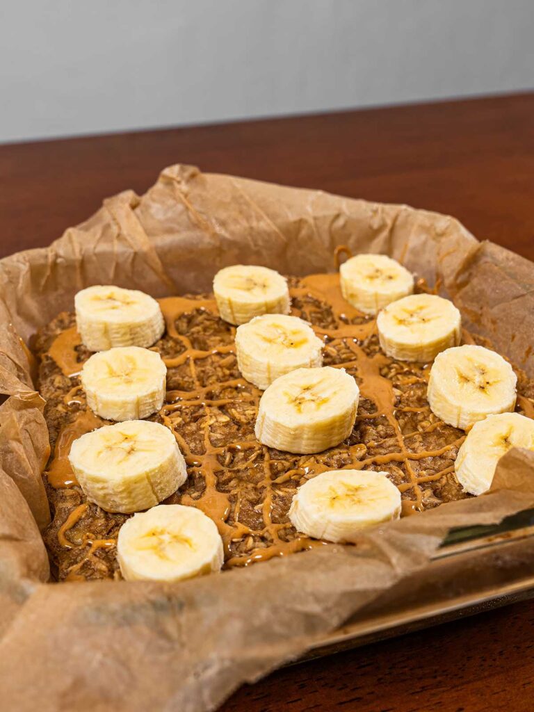 Baked peanut butter banana oatmeal close-up &ndash; creamy high-protein breakfast bake with banana slices