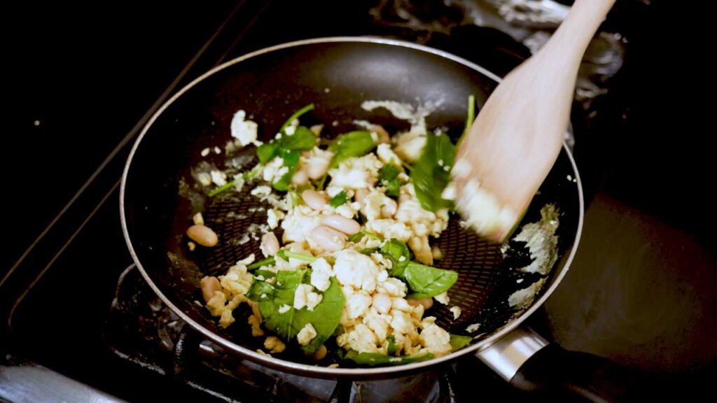 Making breakfast quesadilla &ndash; cooking eggs and chicken in a skillet for high-protein breakfast recipe
