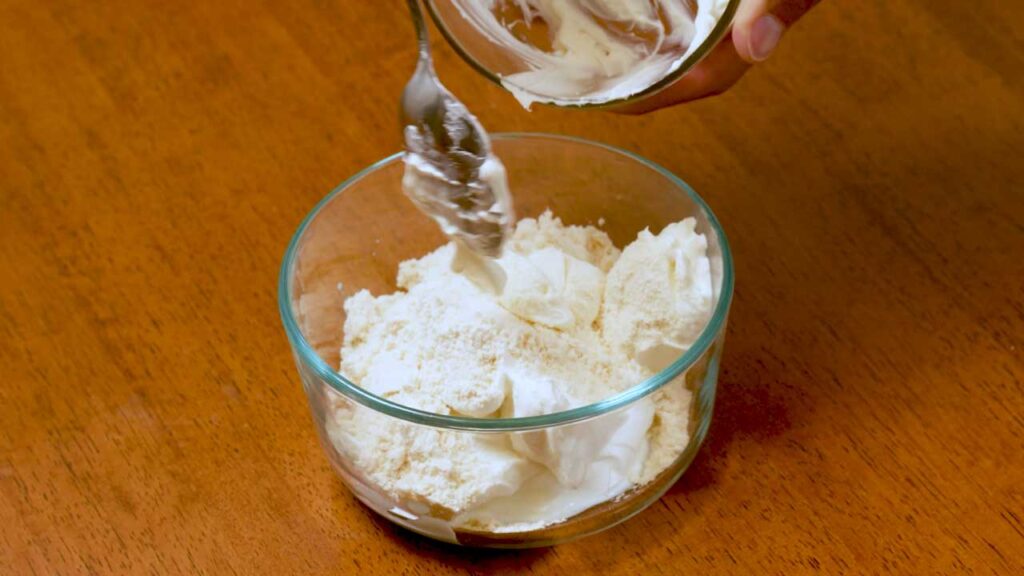 Making cheesecake protein yogurt bowl &ndash; layering cottage cheese and Greek yogurt in a serving bowl