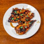 Cilantro lime chicken on a plate with fresh cilantro &ndash; high-protein dinner recipe with lime
