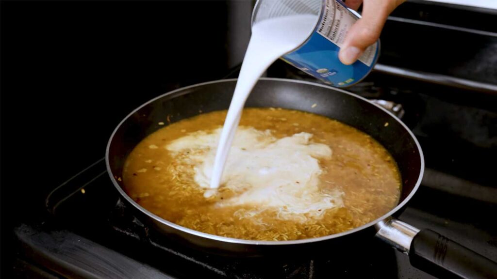 Making coconut curry brown rice &ndash; simmering creamy curry sauce with brown rice for high-protein meal