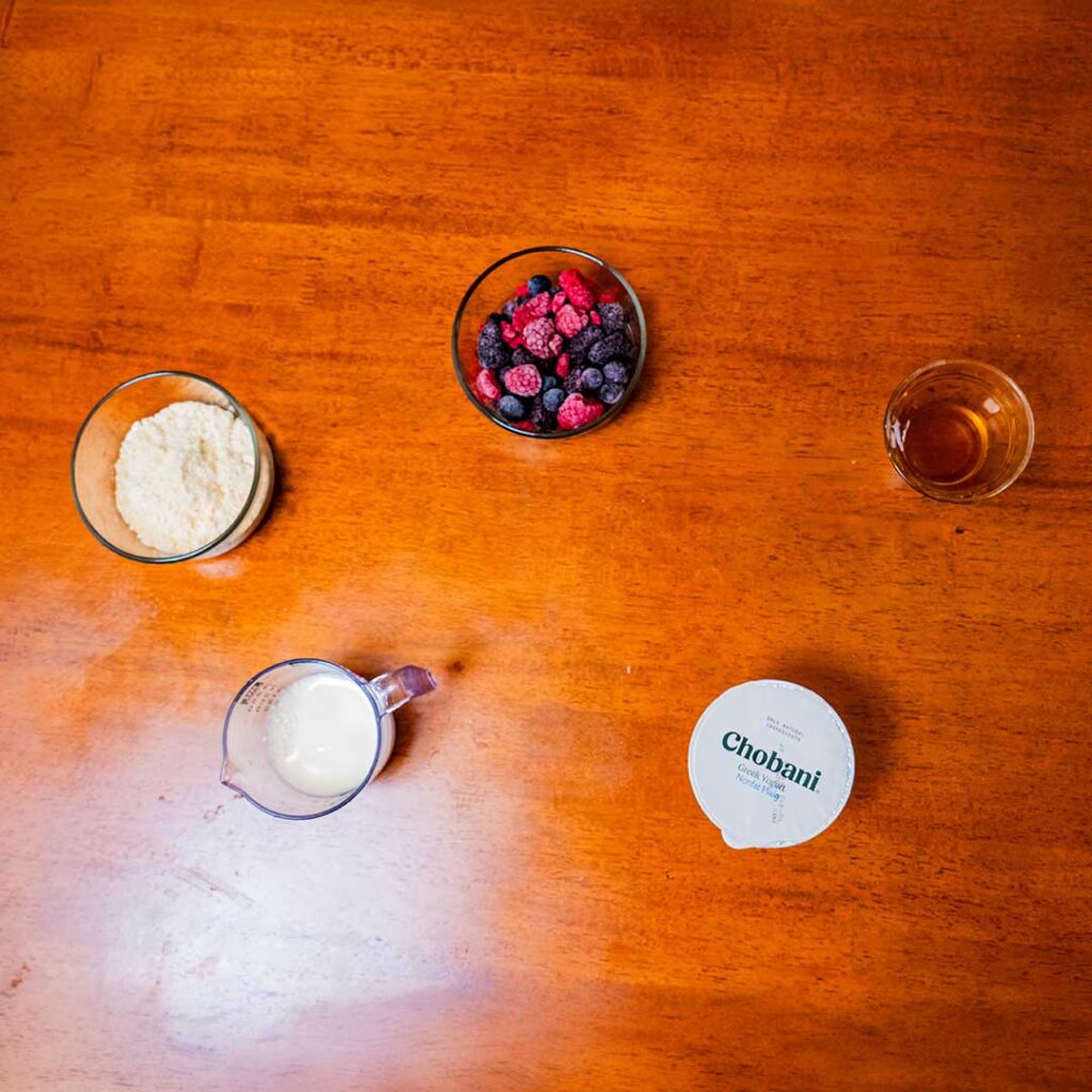 Mixed berry protein shake ingredients – protein powder, strawberries, blueberries for high-protein smoothie
