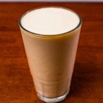 Protein pi&ntilde;a colada &ndash; creamy tropical high-protein smoothie in a glass with pineapple garnish