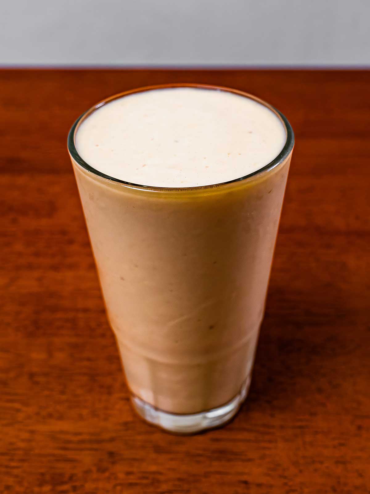 Protein pi&ntilde;a colada &ndash; creamy tropical high-protein smoothie in a glass with pineapple garnish
