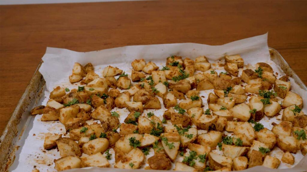 Roasted garlic parmesan potatoes being tossed in seasoning &ndash; high-protein side dish prep