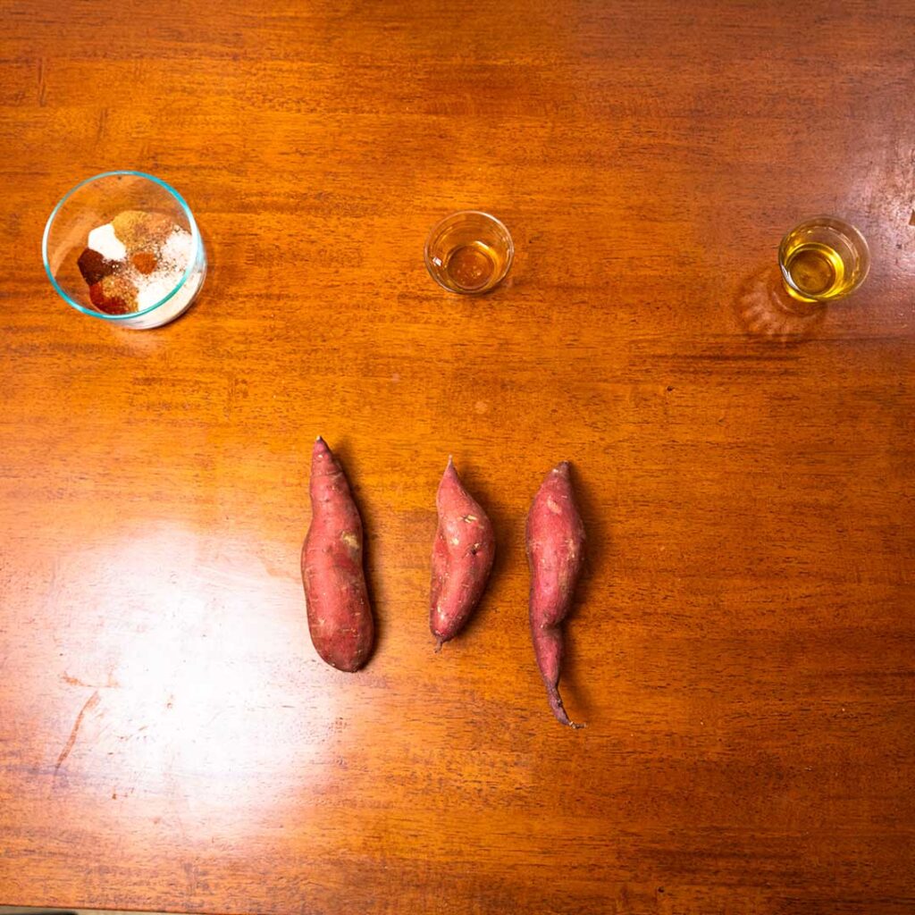 Roasted sweet potatoes ingredients &ndash; fresh sweet potatoes, olive oil, herbs, spices flat lay