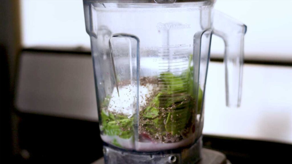 Making spinach acai smoothie &ndash; adding fresh spinach and frozen acai to a blender