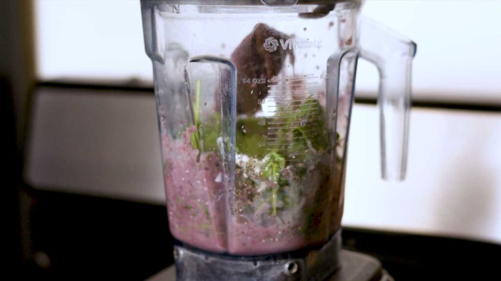 Blending spinach acai smoothie &ndash; vibrant purple mixture swirling in a blender