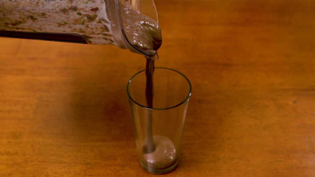 Spinach acai smoothie being poured into a glass &ndash; high-protein healthy breakfast drink