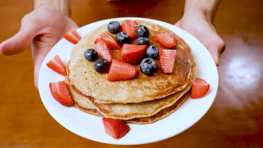 Vanilla protein pancakes overhead flat lay – high-protein breakfast ingredients and finished stack