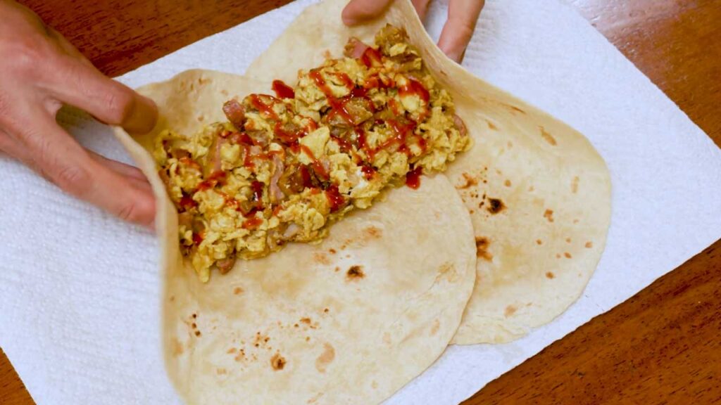 How to make breakfast burrito &ndash; step showing eggs being scrambled in pan