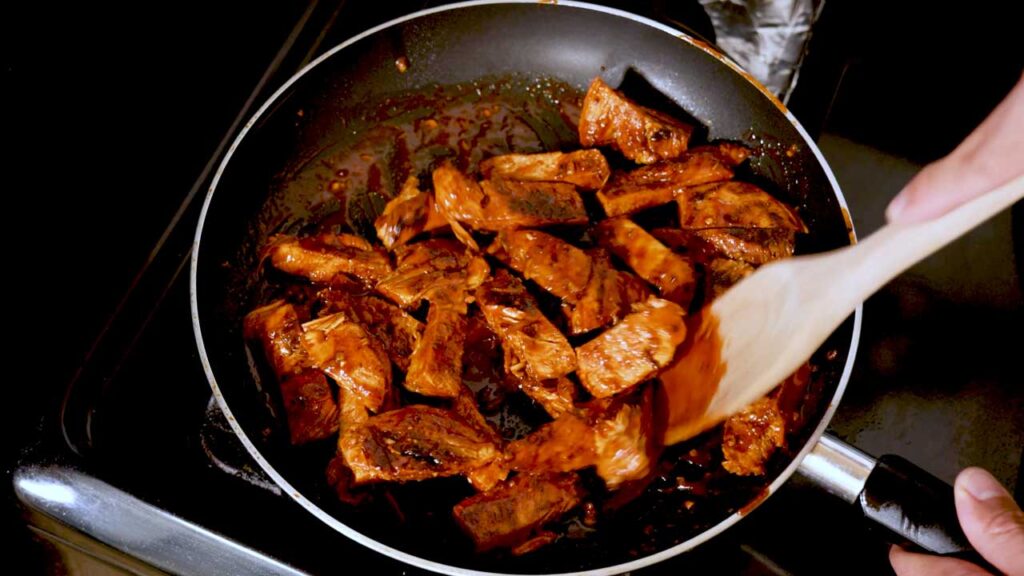 Making Korean chicken meal prep – step 3: portioning chicken into meal prep containers with sides