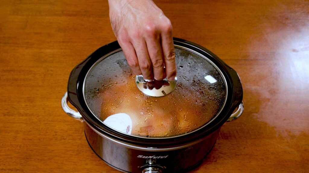 How to make slow cooker BBQ chicken &ndash; step showing BBQ sauce being brushed on cooked chicken