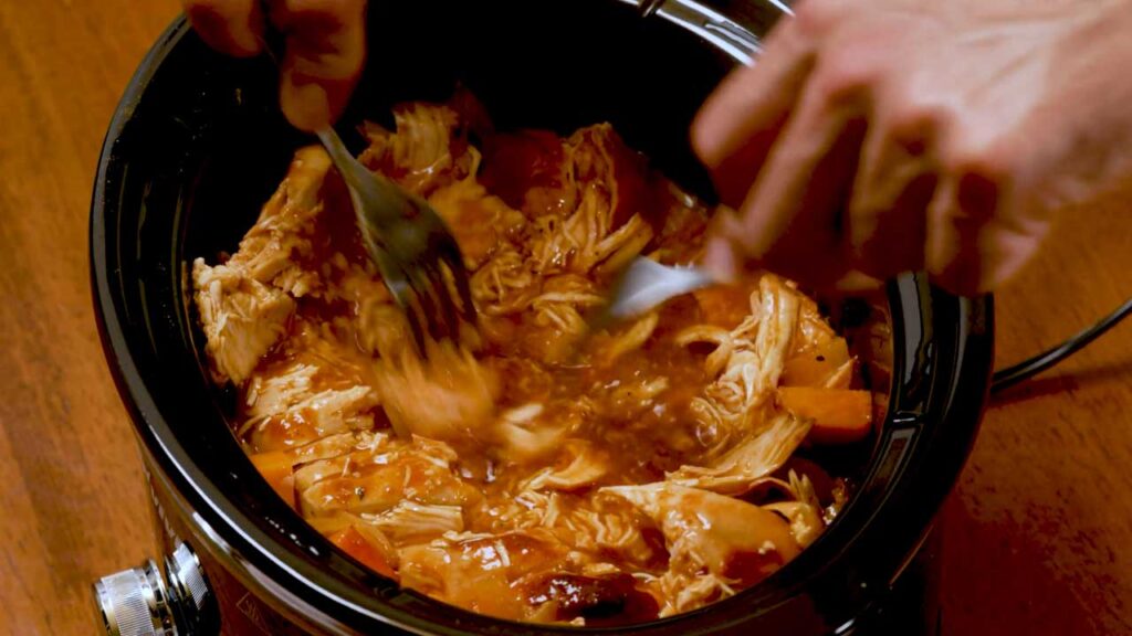 How to make slow cooker BBQ chicken &ndash; step showing finished chicken being sliced and served