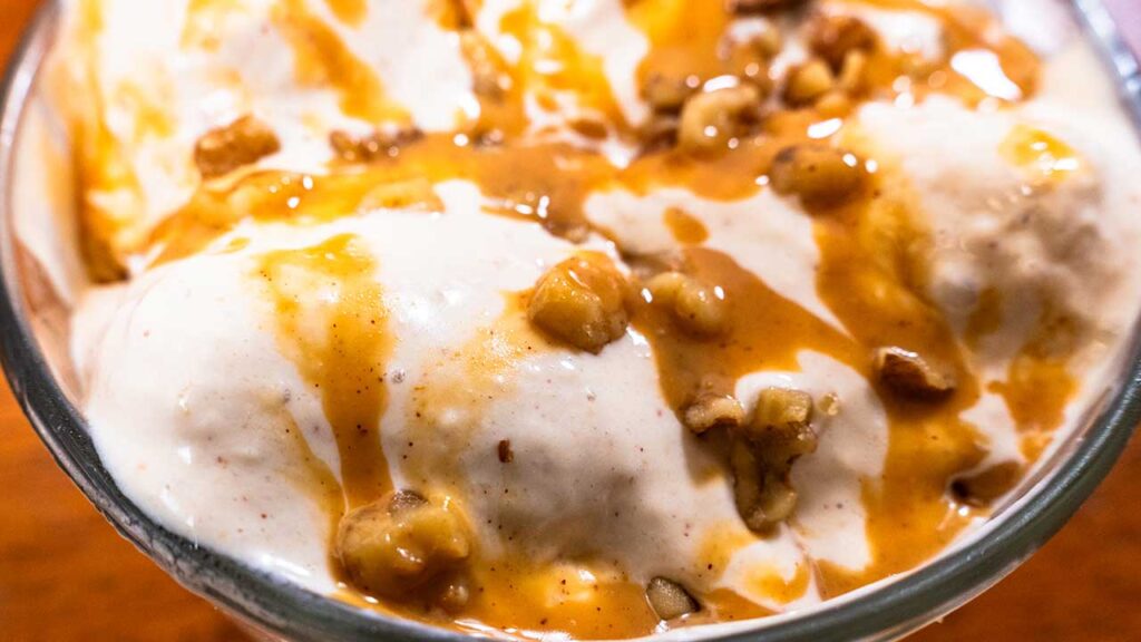 Cottage cheese peanut butter banana ice cream &ndash; single scoop on a spoon with banana garnish