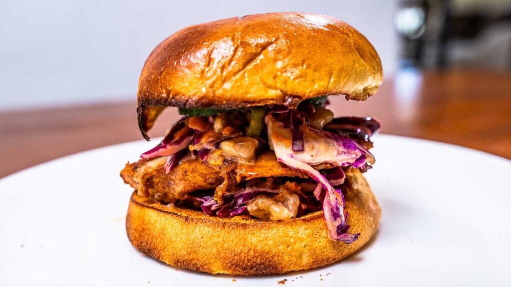 Spicy Asian chicken sandwich flat lay – high-protein lunch with Asian slaw and sauce