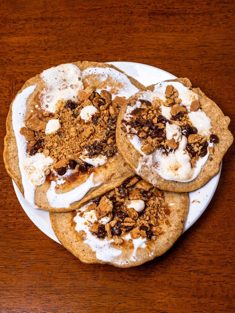 stack of s'mores protein pancakes topped with marshmallow and graham cracker crumbs