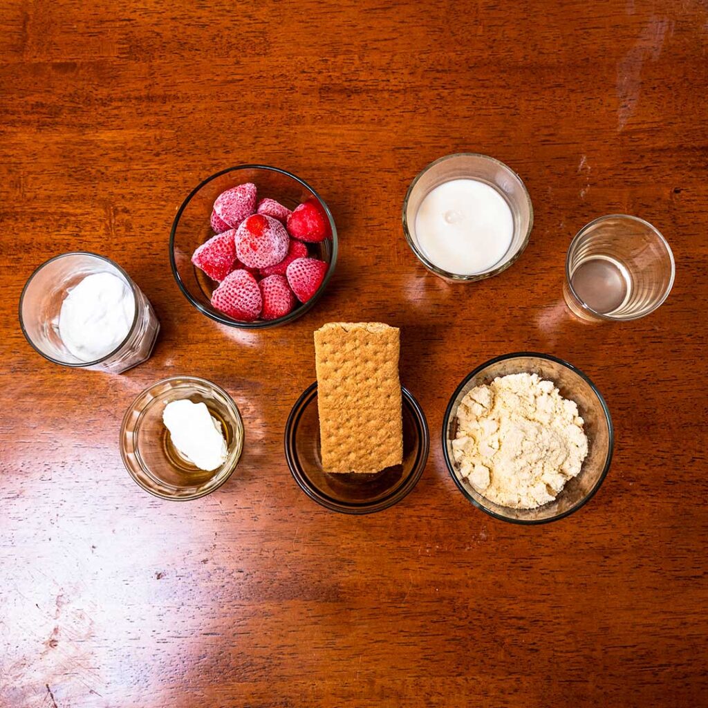 Strawberry cheesecake protein smoothie ingredients &ndash; strawberries, protein powder, and Greek yogurt for a high-protein recipe