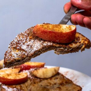 Close-up of apple cinnamon protein french toast on a fork with an apple slice