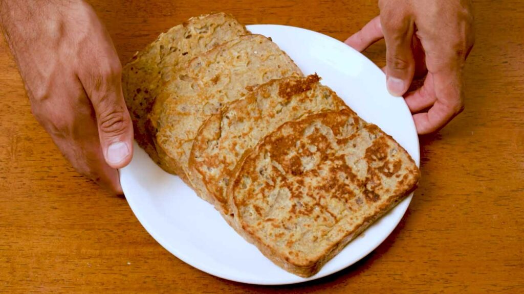 Cooked apple cinnamon protein french toast slices on a white plate before topping with apples