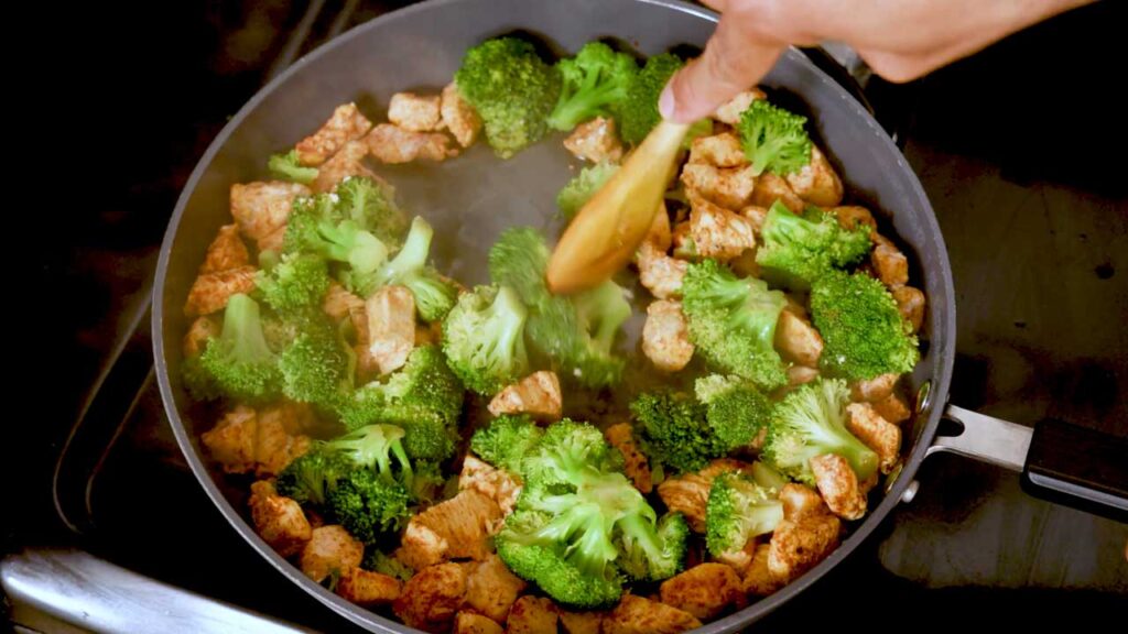 Saut&eacute;ing chicken and broccoli in a skillet for the chicken alfredo pasta recipe