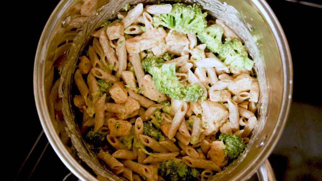 Cottage cheese chicken alfredo pasta mixed together in a pot with chicken and broccoli