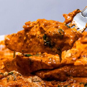 Close-up of marry me chicken in a creamy orange spinach sauce on a fork