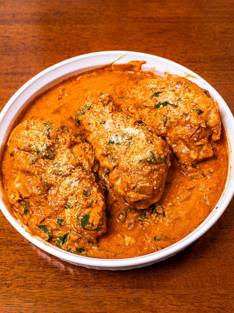 Marry me chicken with spinach and parmesan in a white dish, a high-protein dinner