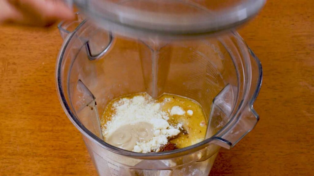 Adding broth and seasonings to a blender for the marry me chicken sauce