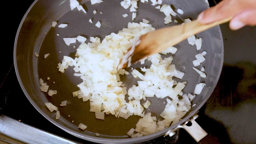Saut&eacute;ing diced onions in a skillet for the marry me chicken recipe