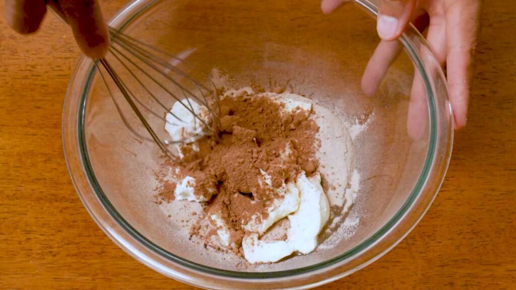 Whisking cream cheese, cocoa powder, and protein powder for chocolate protein cheesecake