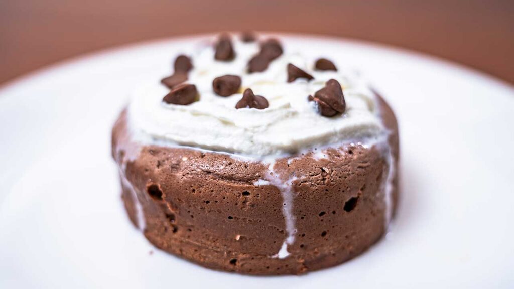 Finished microwave chocolate protein cheesecake with whipped cream and chocolate chips