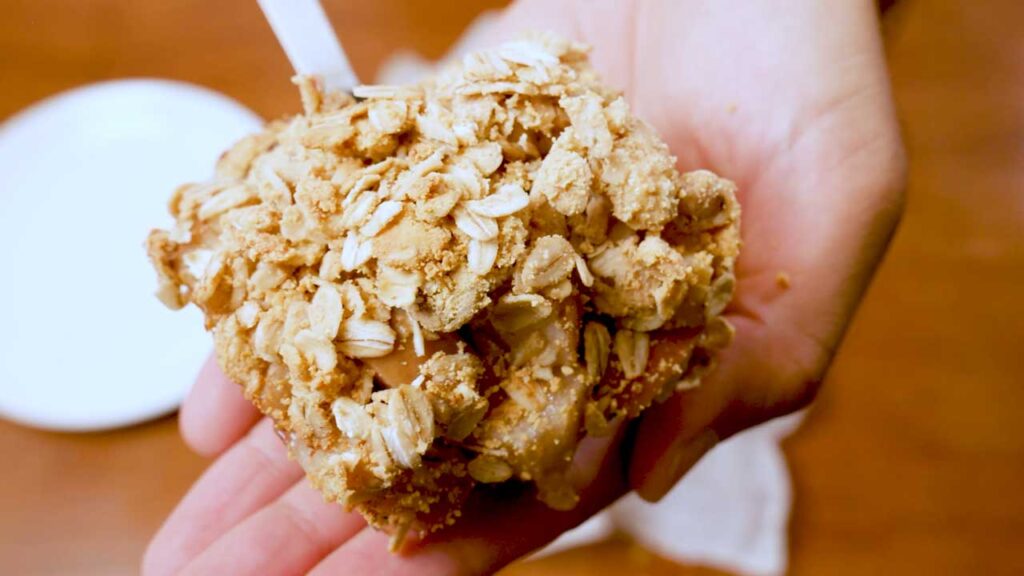 Scoop of baked high-protein apple crisp held in hand, ready to eat