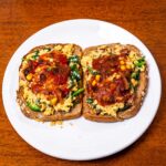 Two slices of toast with tex-mex cottage cheese scrambled eggs and salsa on a plate
