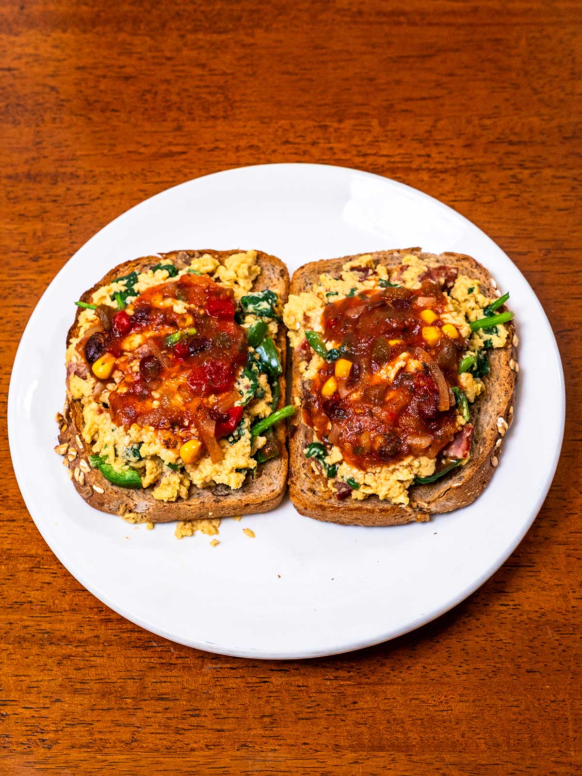 Two slices of toast with tex-mex cottage cheese scrambled eggs and salsa on a plate