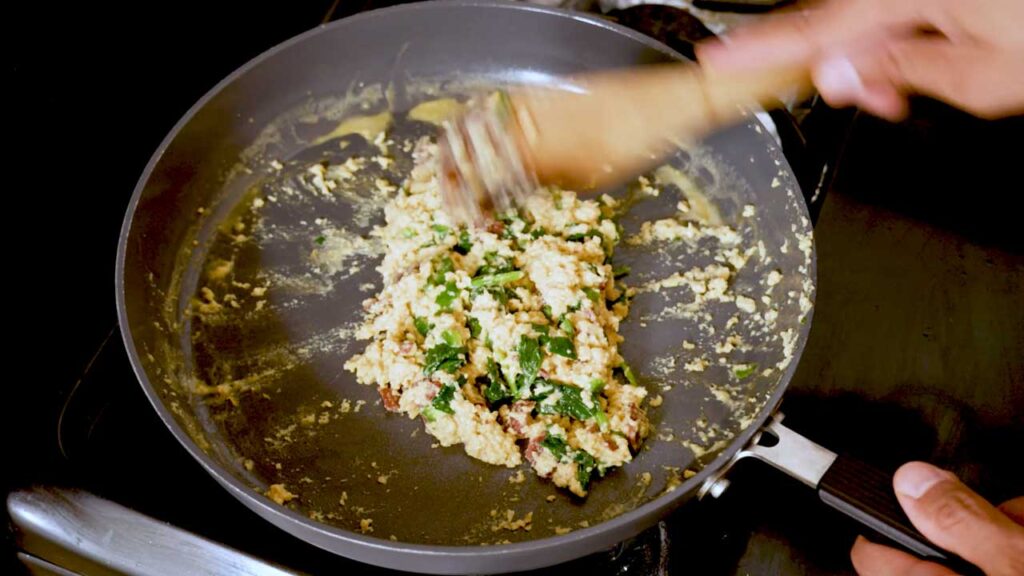 Scrambling the eggs, spinach, and chorizo together until fully set