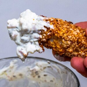 Crispy air fryer fish stick dipped in creamy tartar sauce, a high protein snack