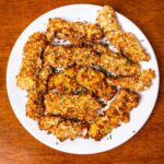 Golden crispy air fryer fish sticks on a white plate, easy high protein dinner