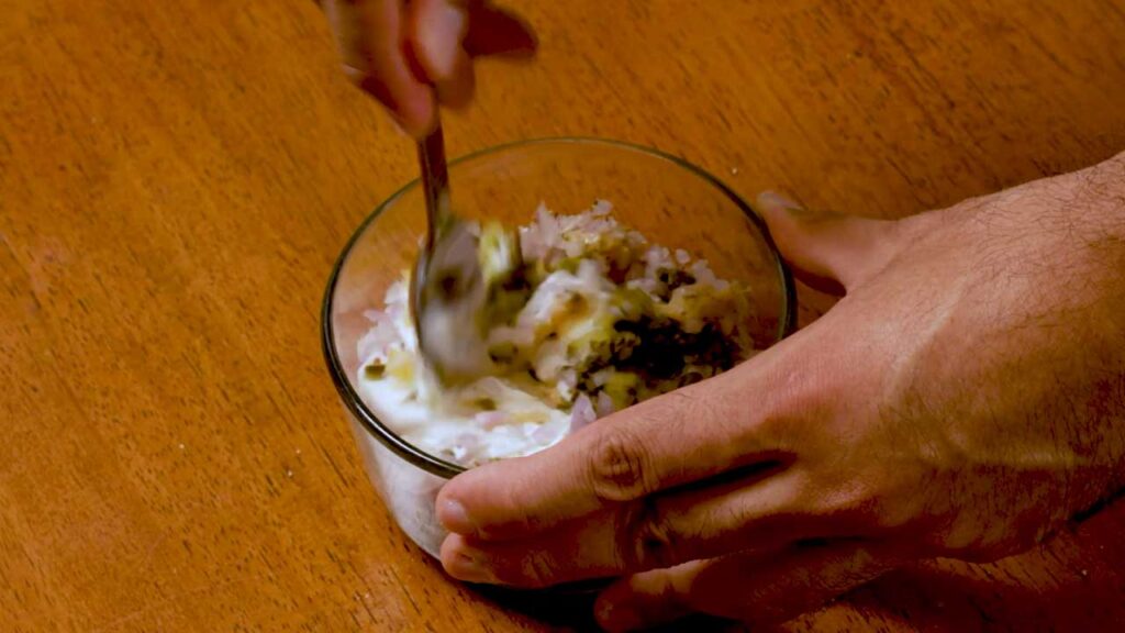 How to make tartar sauce, stirring yogurt, shallots, pickles, and herbs in a bowl