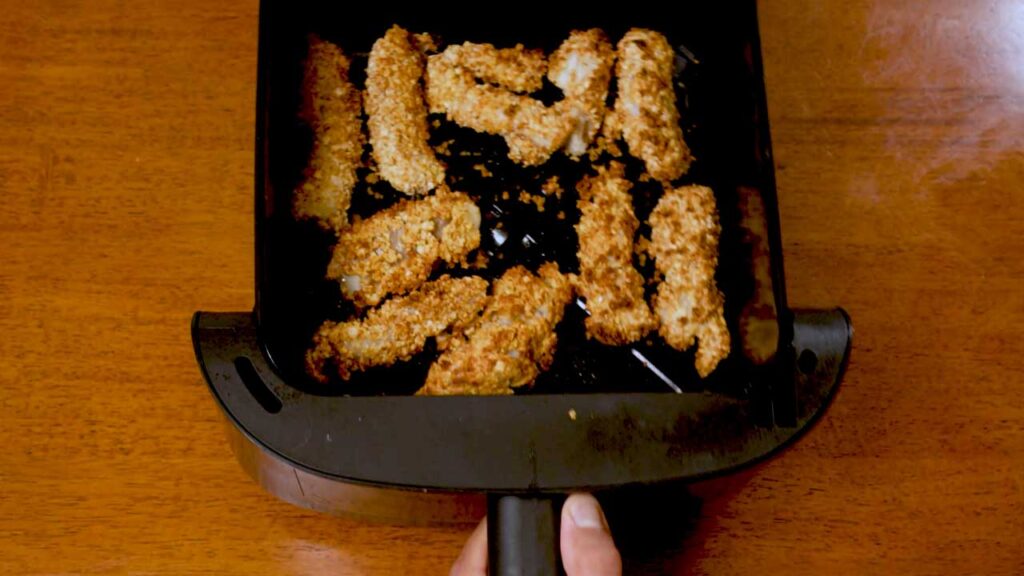 Cooked golden fish sticks in an air fryer basket fresh out of the air fryer