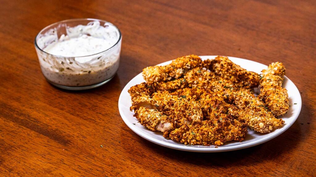 Plated air fryer fish sticks with creamy dipping sauce, a high protein dinner