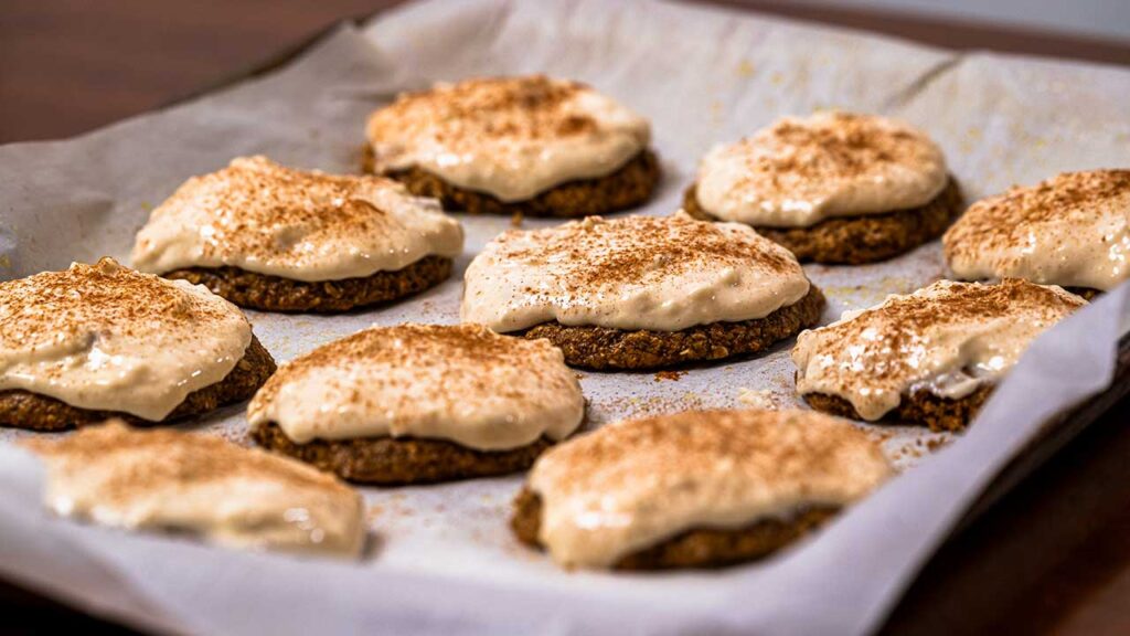 Frosted gingerbread protein cookies on a parchment-lined baking sheet