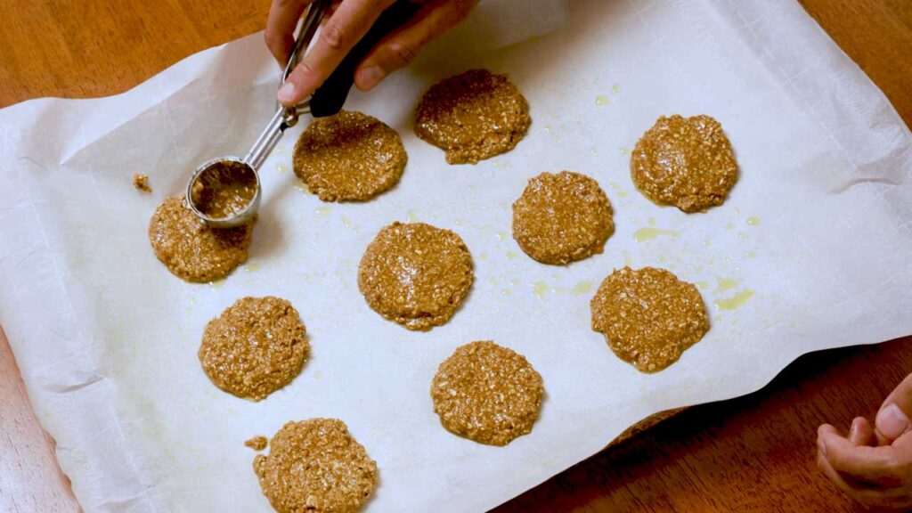 Scooping raw gingerbread protein cookie dough onto parchment paper